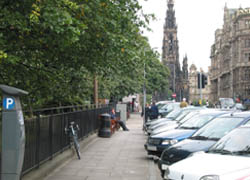 A row of cars parked in front of a pavement in Edinburgh.